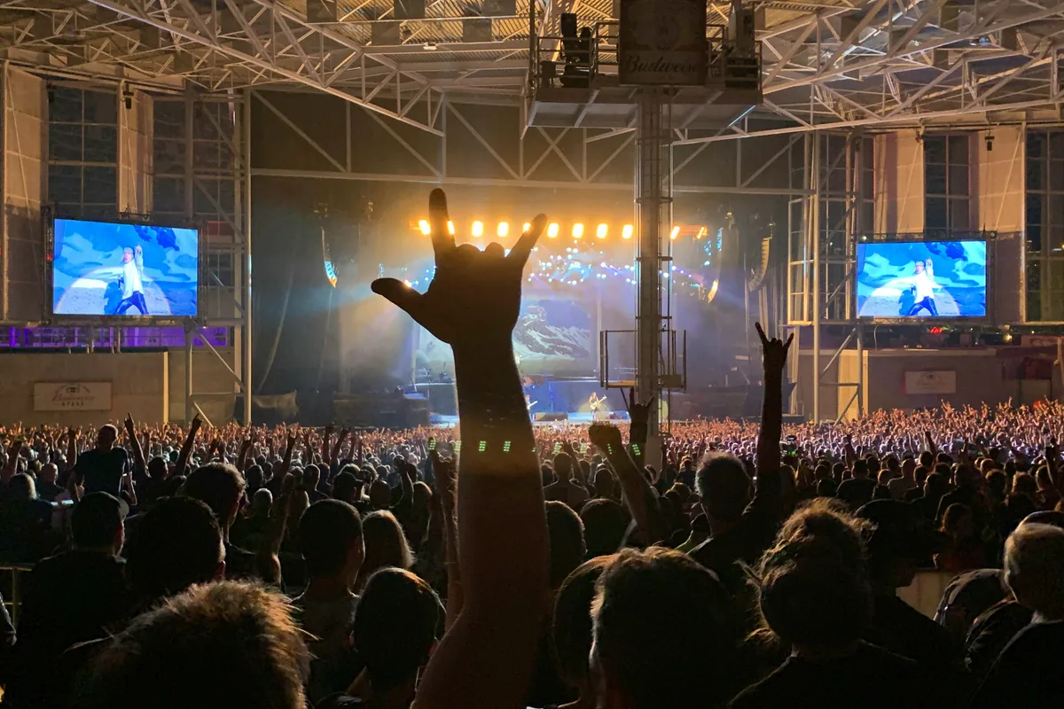 Concert crowd with hands raised in front of a lit stage
